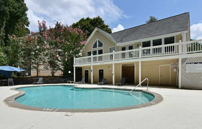 the pool is in front of a large house with a porch