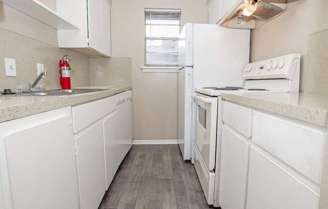 A kitchen with white appliances and cabinets  at The Creole Apartments in Shreveport, LA