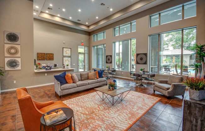 a living room with couches and chairs and large windows