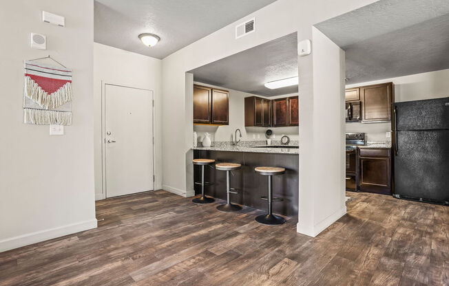 a kitchen with a bar with stools and a refrigerator