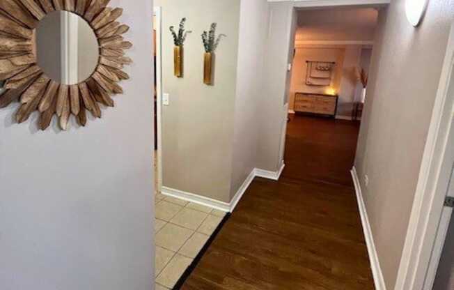 A hallway with a mirror and two vases on the wall.