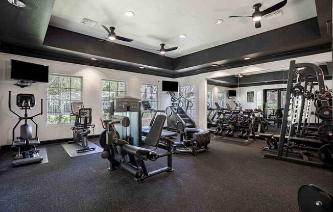 A spacious gym with a variety of equipment including treadmills, stationary bikes, and weight machines.
