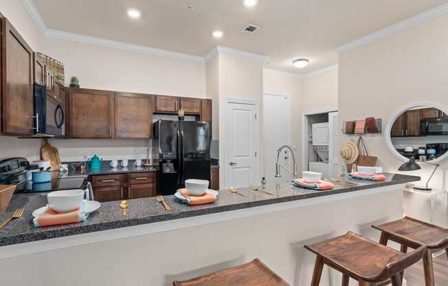 a kitchen with a bar and stools in front of a counter with a sink