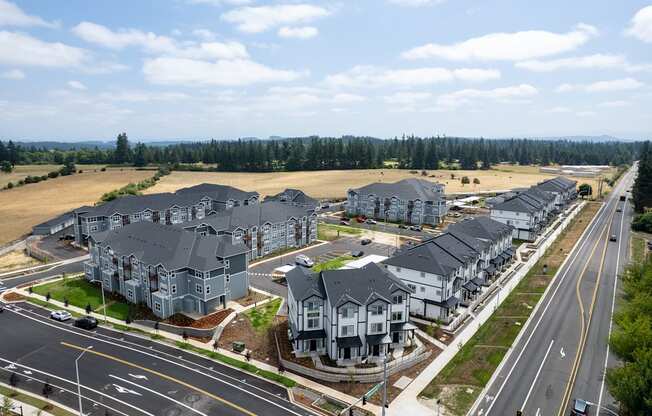 A row of houses are built on a street with a grassy field in the background.