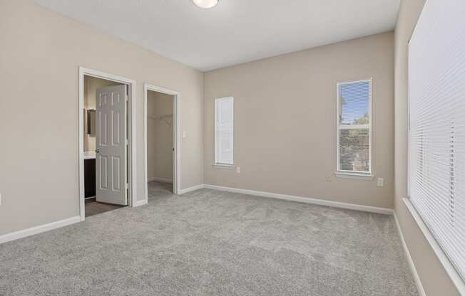 an empty living room with white blinds and a door to a bathroom