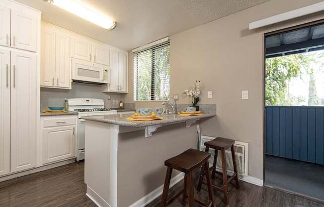 A kitchen with white cabinets and a grey island.