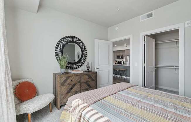 A bedroom with a bed, chair, and a dresser with a mirror.