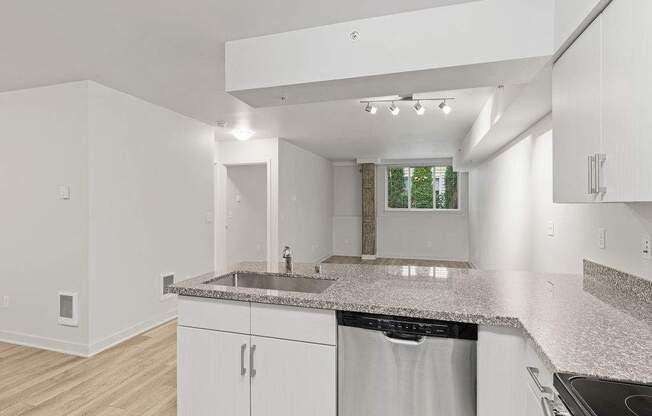 A kitchen with white cabinets and a granite countertop.