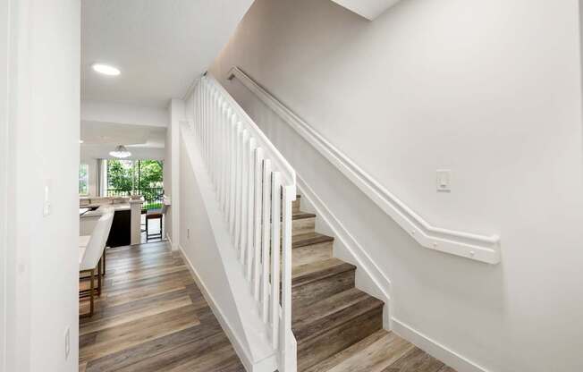 an image of a staircase in a home with wood floors and white railings