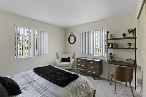 a bedroom with a bed and a desk with a chair and a dresser  at Camelot Apartment Homes, Everett, WA