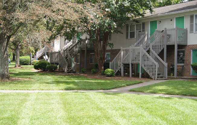 the front of a building with stairs and grass and trees
