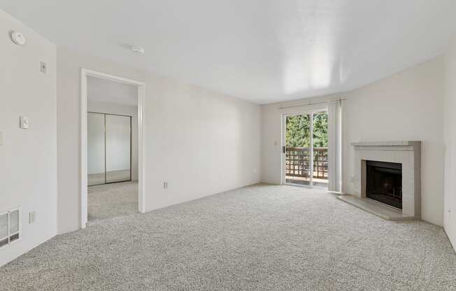 A large, empty room with a fireplace and a carpeted floor.