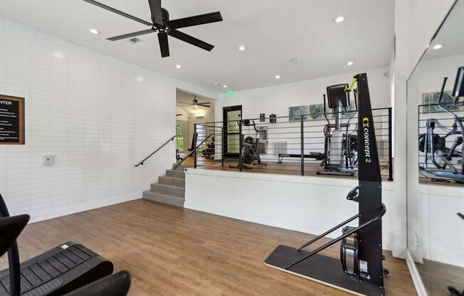 A gym with a variety of equipment including a squat rack and a bench.