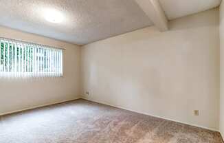 the spacious living room of an empty home with a window