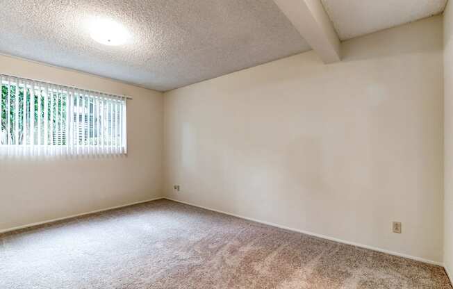 the spacious living room of an empty home with a window