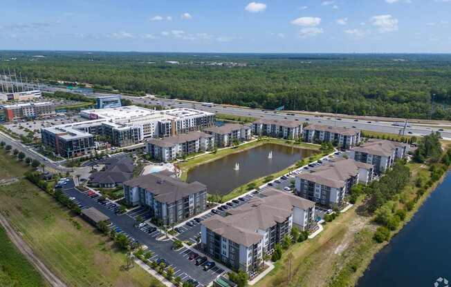 A bird's eye view of a residential area with a lake and apartment buildings.