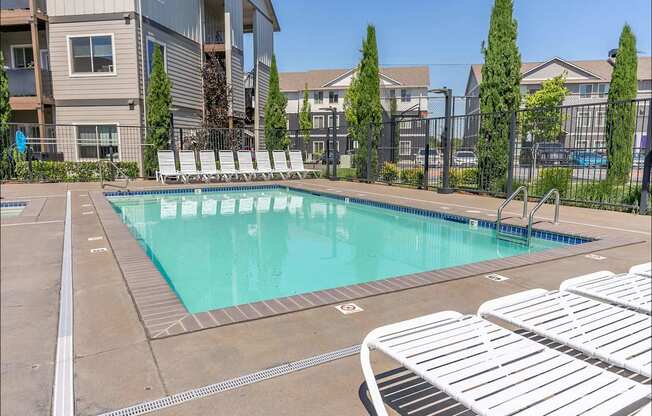 A swimming pool surrounded by white lounge chairs at Timberridge Place Apartment Homes, Oregon