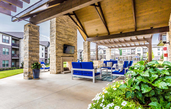 a covered patio with blue chairs and a fireplace