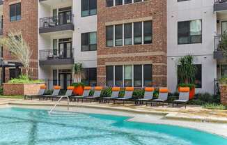 A pool area with chairs and a building in the background.