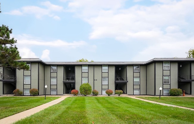 A large apartment complex with a grassy front yard.