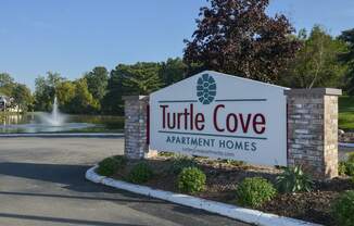 the sign for turtle cove apartment homes in front of a fountain