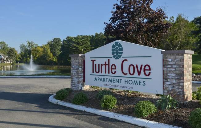 the sign for turtle cove apartment homes in front of a fountain