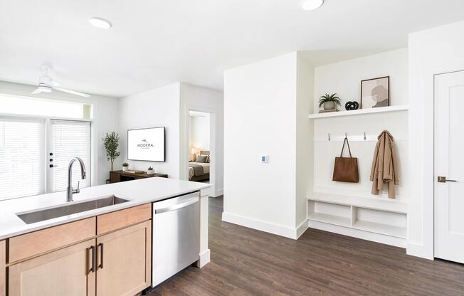 Open kitchen and living area with a central island, light wood cabinetry, and a built-in entry drop zone that keeps daily essentials organized.