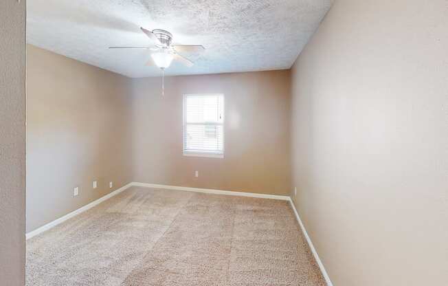 A room with a ceiling fan and carpeted floor.