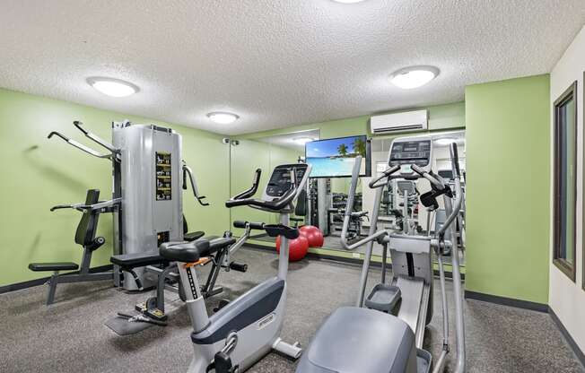 a gym with exercise equipment and green walls