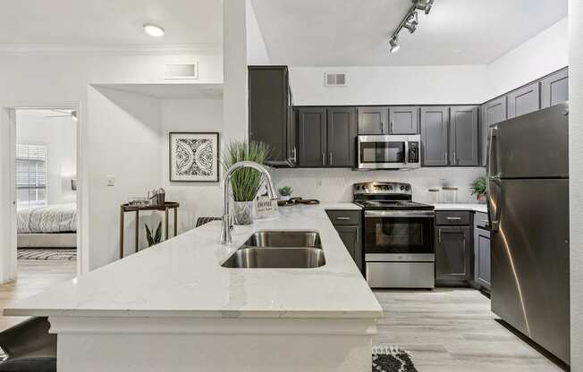 A modern kitchen with a white countertop and stainless steel appliances.