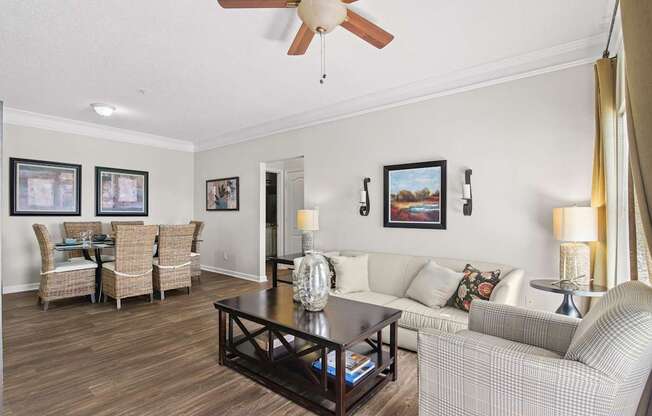 A living room with a couch, chairs, and pictures on the wall.