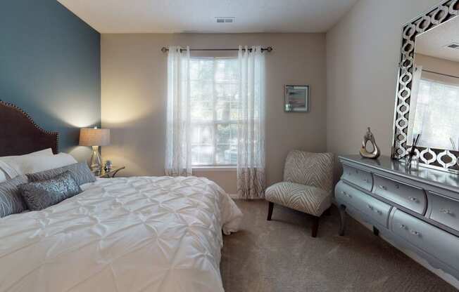 a bedroom with a large bed and a dresser with a mirror at Autumn Park Apartments, Charlotte, NC, 28262