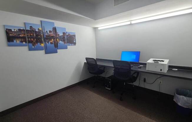 A room with a desk, computer, and pictures on the wall.