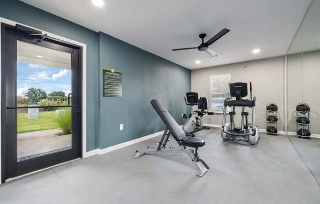 A gym room with a row of exercise machines and a chair.
