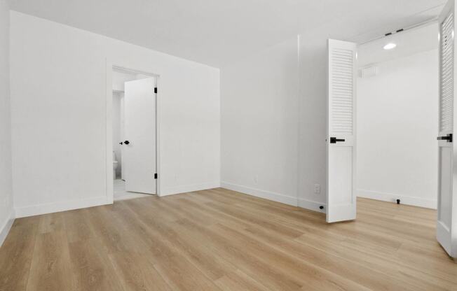 an empty room with white walls and wooden floors