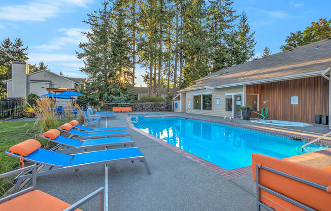 A pool with sun loungers and a building in the background.