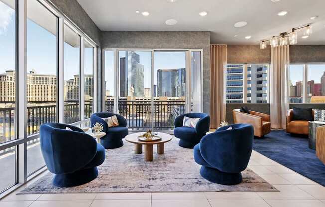 A living room with blue chairs and a view of the city.
