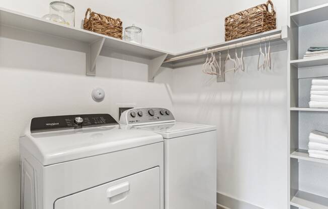 a white washer and dryer in a laundry room with shelves