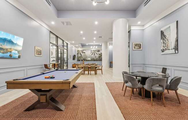 A room with a pool table and a dining table.