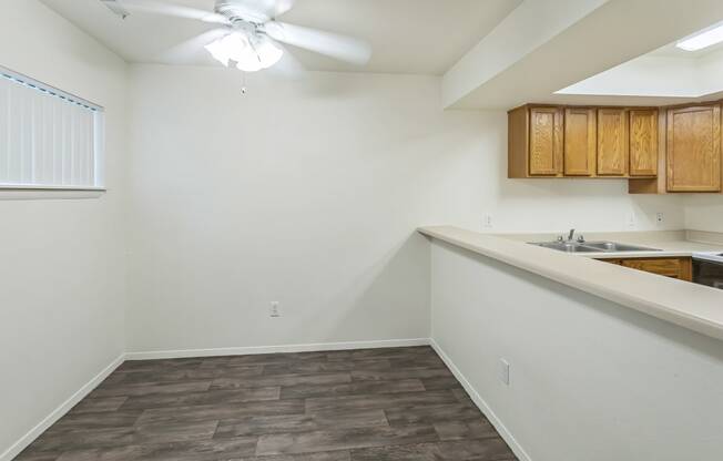 an empty kitchen with wood flooring and a ceiling fan