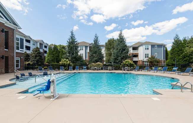 A swimming pool surrounded by lounge chairs and trees.