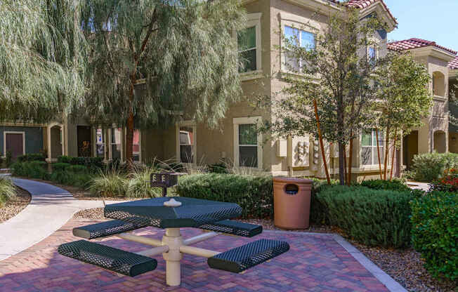 A green picnic table is in the middle of a brick patio.