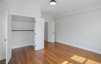 an empty living room with wood flooring and an open closet