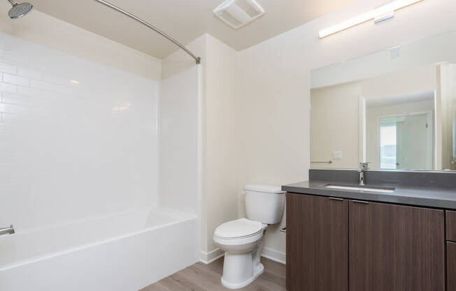 A white toilet sits next to a white bathtub in a bathroom.