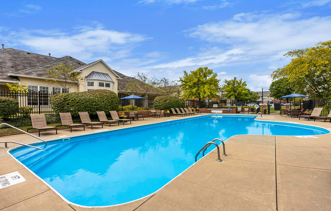 a swimming pool with chairs and a house in the background
