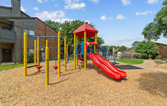 A playground with a red slide and yellow poles.
