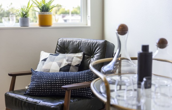 a living room with a black leather couch and pillows on it at Analog PDX Apartments, Portland, OR 97227