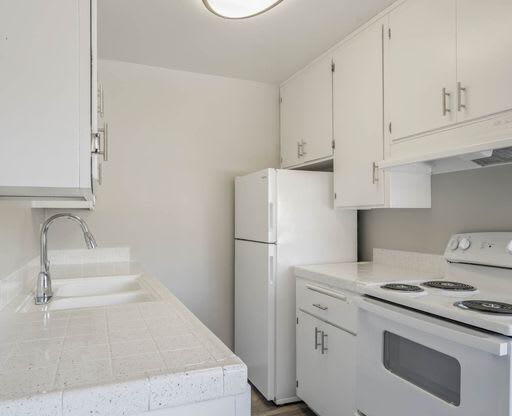 a kitchen with a stove and a sink and a refrigerator at The Arches Apartments, El Cajon California