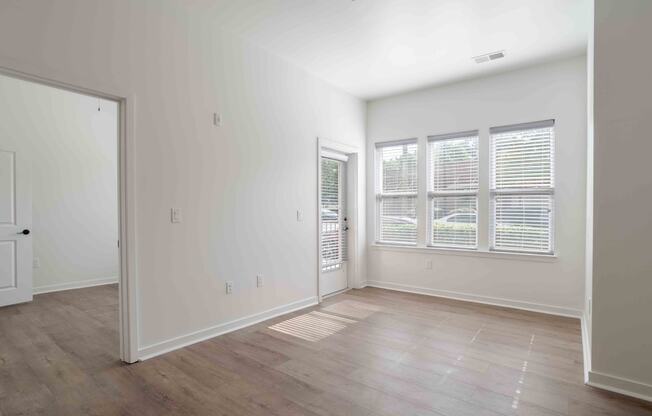 an empty living room with white walls and wood floors