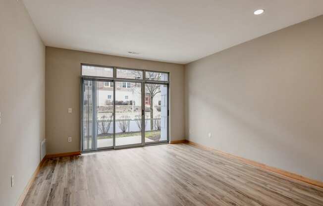 an empty living room with a sliding glass door to a balcony